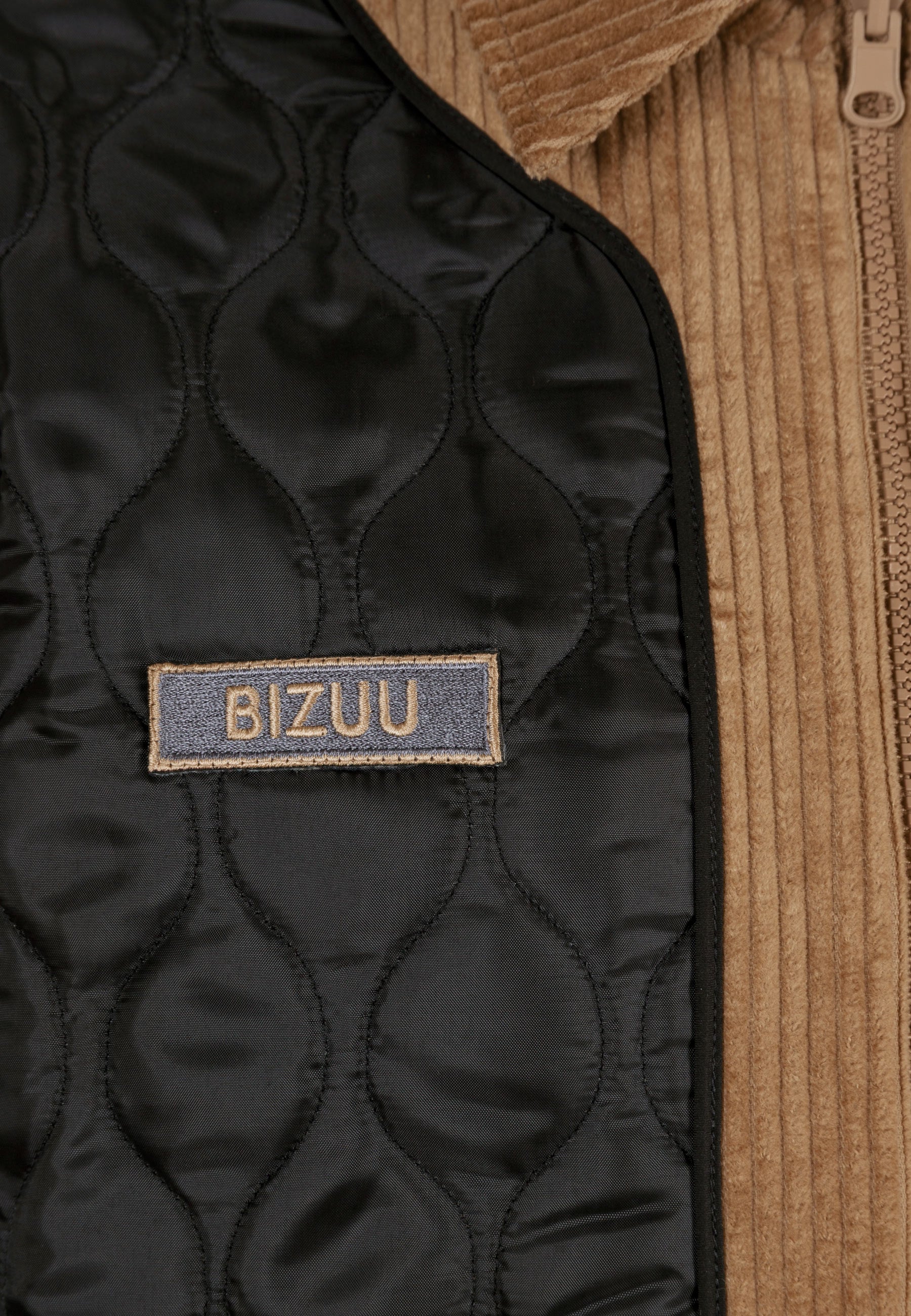 Zbliżenie na logo na dwustronnej, pikowanej kurtce BAIONA.