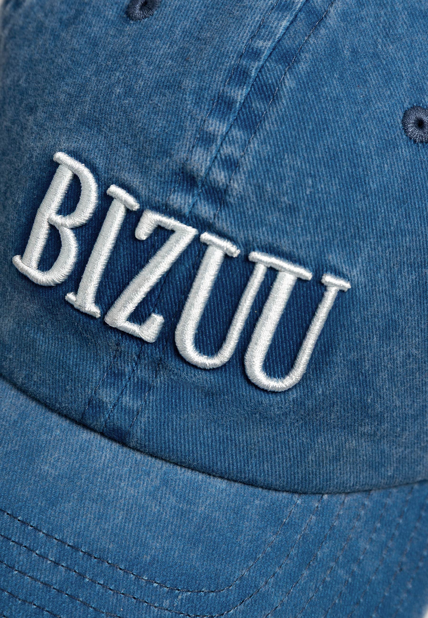 Zbliżenie na logo haftowane na przodzie czapki z daszkiem ZANE.